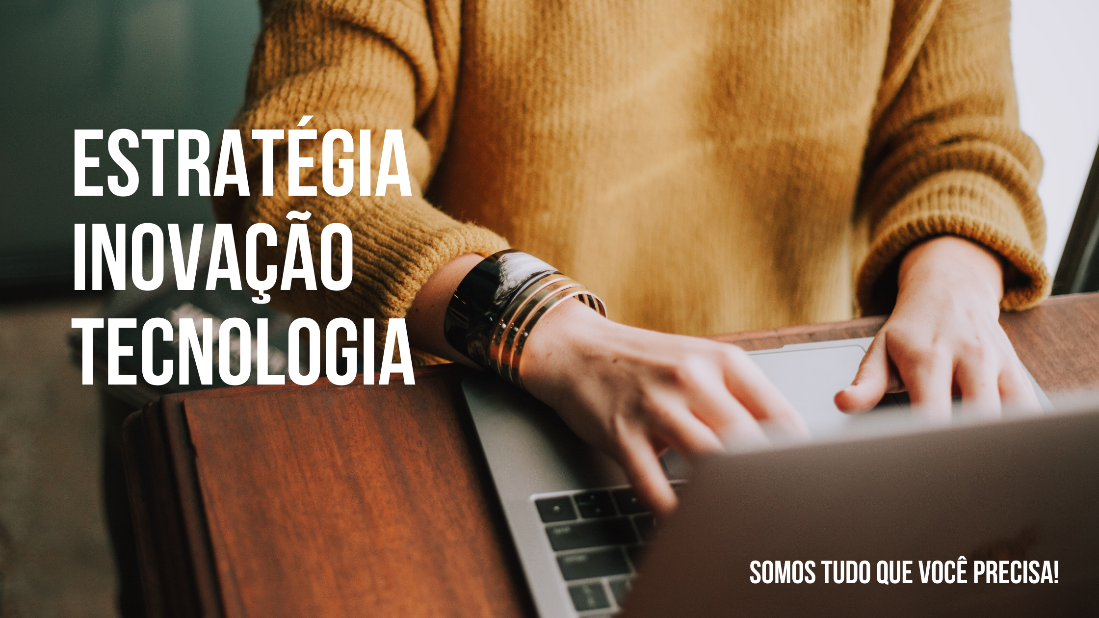 mulher digitando em frente ao notebook, em cima de uma mesa de madeira.